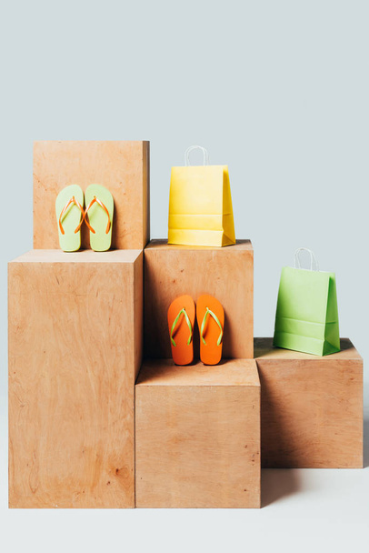 colored paper bags and flip flops on wooden stands, summer sale concept - 写真・画像