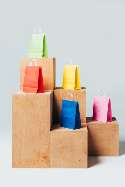 цветные сумки для покупок на деревянных стендах, концепция летней продажи
 - Фото, изображение