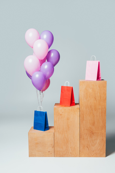 bundle of pink and violet balloons near shopping bags on stands, summer sale concept - Photo, image