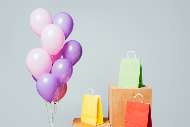 bundle of pink and violet balloons near shopping bags on stands isolated on white, summer sale concept - Photo, Image