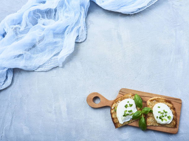 Oeuf poché savoureux avec des feuilles de basilic fraîches sur pain grillé sur planche à découper sur fond de pierre de béton bleu ou de marbre
 - Photo, image