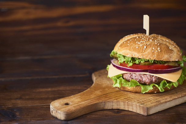 Fresh Tasty burger on cutting board over wooden background - Zdjęcie, obraz