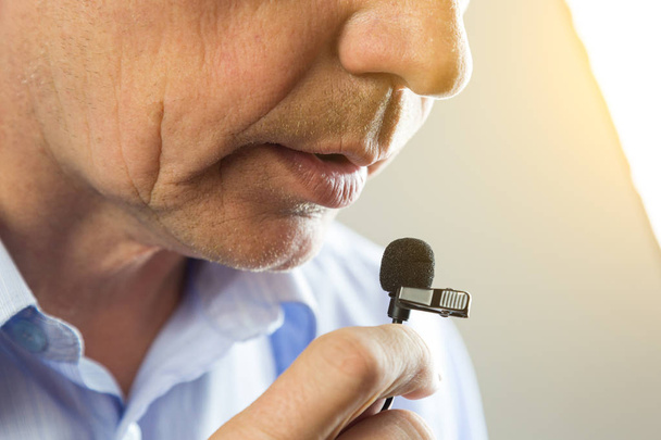 The man speaks into a small microphone in a low voice. - Photo, image