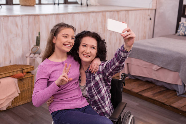 Joyful crippled woman and girl taking selfie - Valokuva, kuva