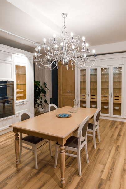 Stylish kitchen with elegant wooden table and chandelier - Valokuva, kuva