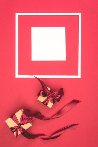 Ansicht von Geschenkboxen mit Schleifen und Rahmen mit Würfel auf roter Oberfläche - Foto, Bild