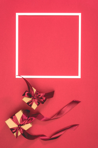 elevated view of gift boxes and frame on red surface - Foto, afbeelding