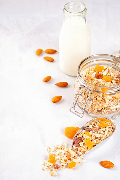 Jar with homemade granola or oatmeal muesli with nuts and dried fruits and almond milk. Healty diet breakfast, vegan or vegeterian food concept - Foto, immagini