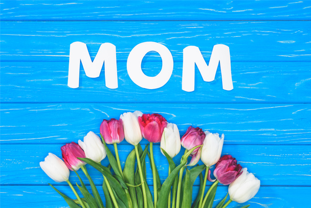 elevated view of bouquet of pink and white tulips and word mom on blue table, mothers day concept - Fotografie, Obrázek
