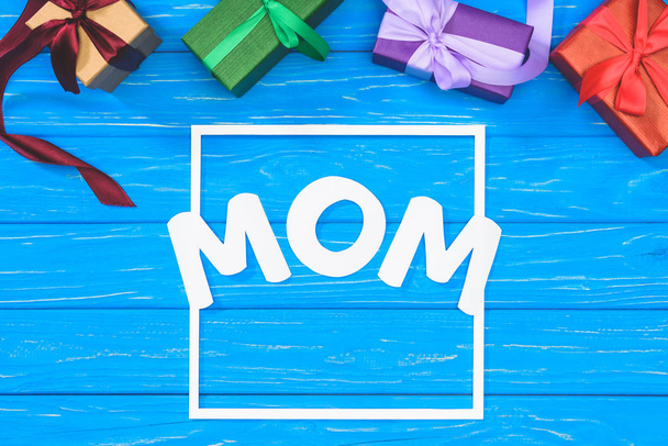 top view of gift boxes and word mom in frame on blue table, mothers day concept - Photo, image