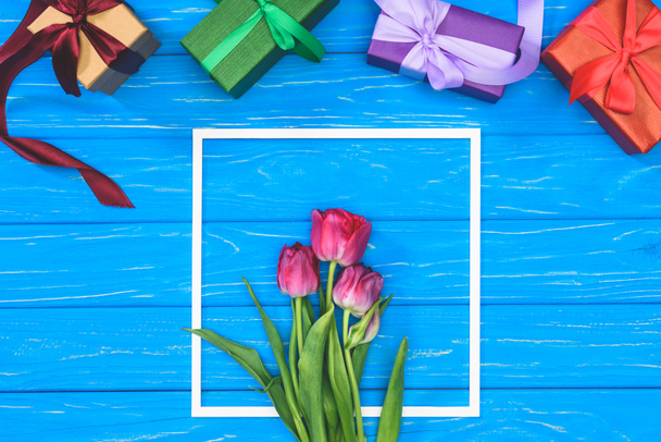 top view of gift boxes and pink tulips in frame on blue table - Photo, Image