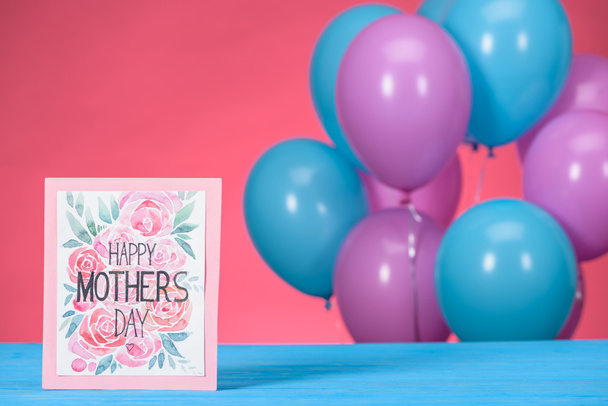 cartão postal com texto Feliz Dia das Mães e azul com balões violeta no fundo
 - Foto, Imagem