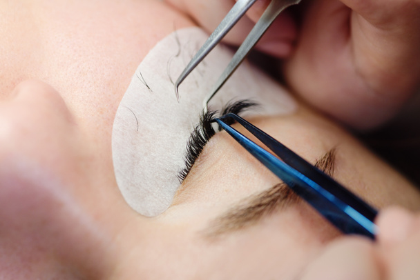 Woman eye with long eyelashes - eyelash extension procedure,  close up, macro, selective focus. - Фото, зображення