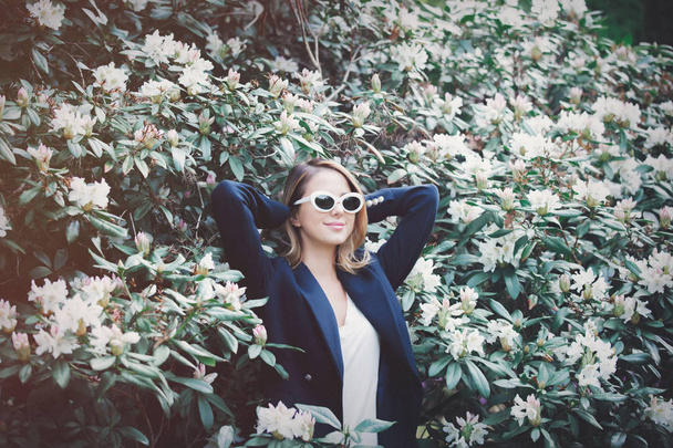 дівчина в білих сонцезахисних окулярах біля квітів
 - Фото, зображення