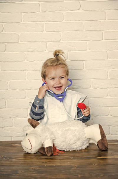 Happy child play doctor with toy sheep on white wall - Zdjęcie, obraz