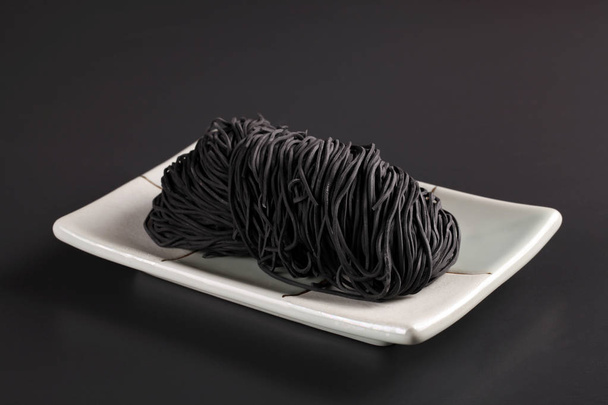 Closeup of white plate with Chinese noodle on black background - Photo, image