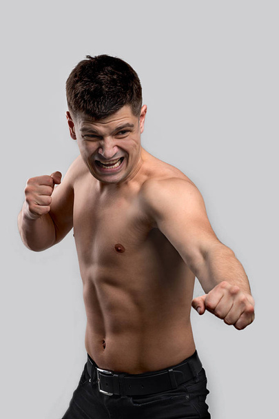 The muscled man on a grey background in  fighting pose  - Foto, immagini