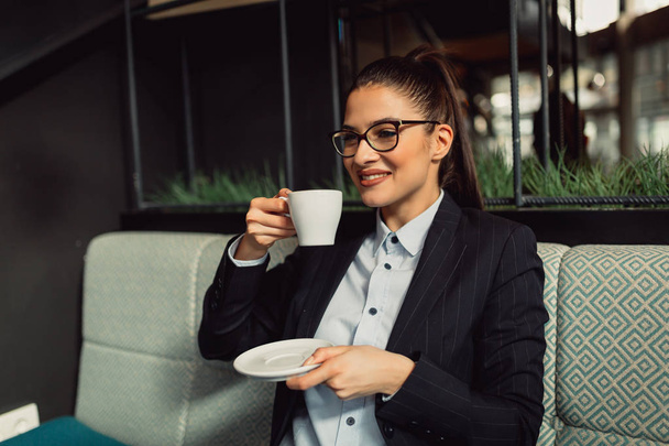 Attractive brunette woman enjoys drinking coffee on her break - Foto, imagen