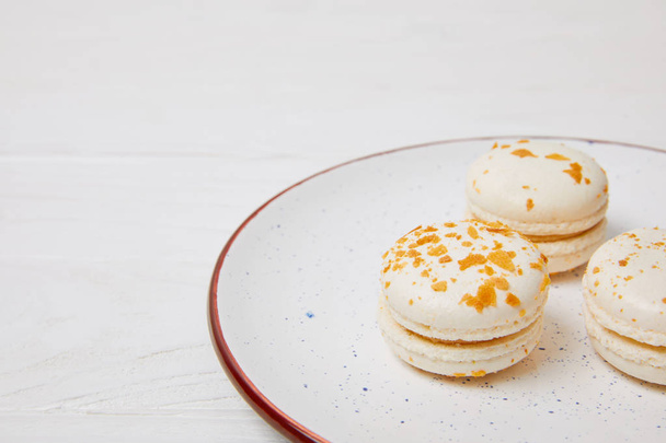 closeup view of macarons in plate on white wooden table  - Valokuva, kuva