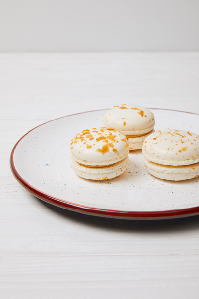 three macarons in plate on white wooden table  - 写真・画像