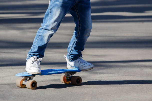 Pequeno o rapaz de calça azul-clara que aprende a patinar de patins no parque de verão. Desporto ao ar livre ativo para crianças. Close up vista das pernas no patins
 - Foto, Imagem