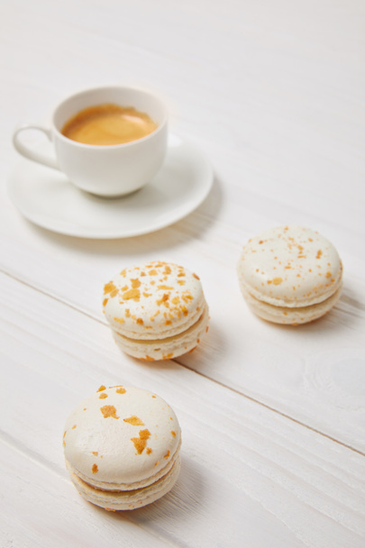closeup shot of coffee cup and three macarons on white wooden table  - 写真・画像