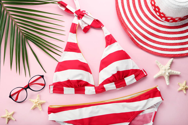Red swimsuit with starfishes and palm leaf on pink background - Foto, Imagem