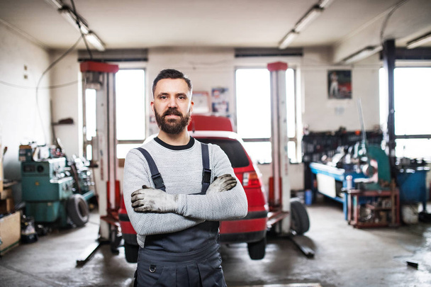 Portrait of a man mechanic in a garage. - 写真・画像
