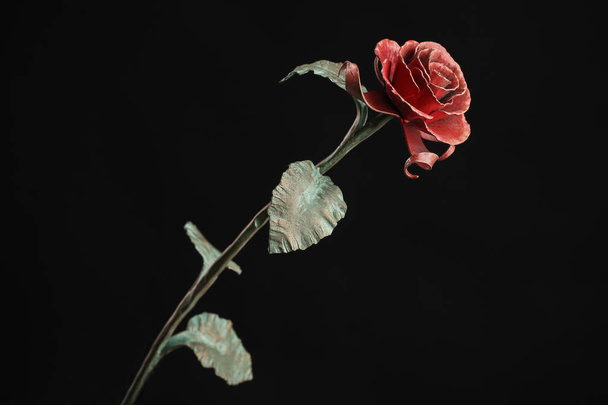 The metal rose with a red bloom and a green stalk, on black background. - Foto, imagen