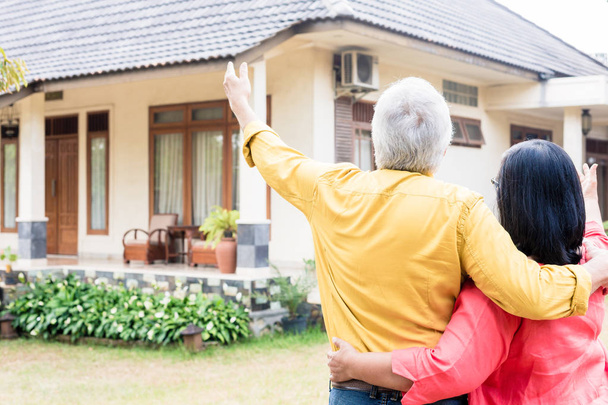 Homme âgé pointant vers sa femme une maison d'habitation confortable
 - Photo, image