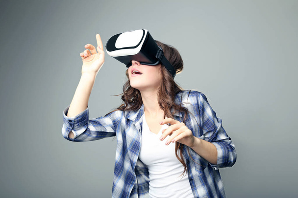 Young girl in virtual reality goggles on grey background - Foto, Imagem