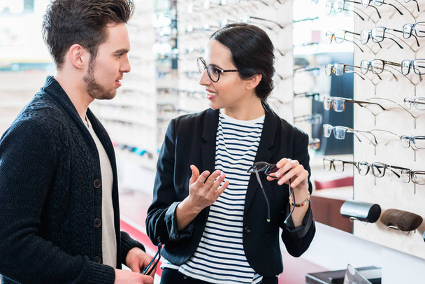 мужчина и женщина покупают очки в магазине оптики - Фото, изображение