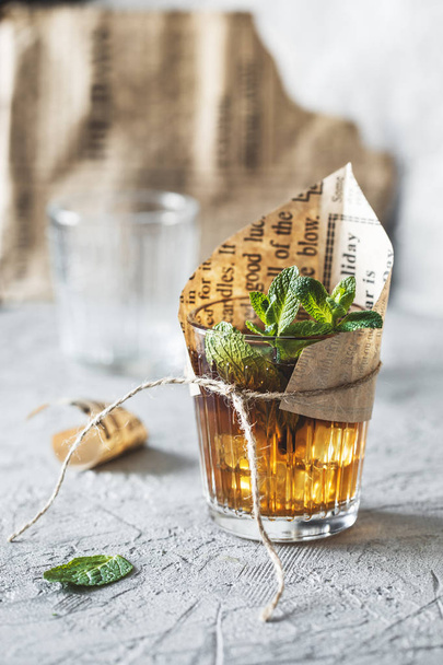 closeup view of herbal tea with mint leaves in glass with tied paper piece - Foto, Imagen