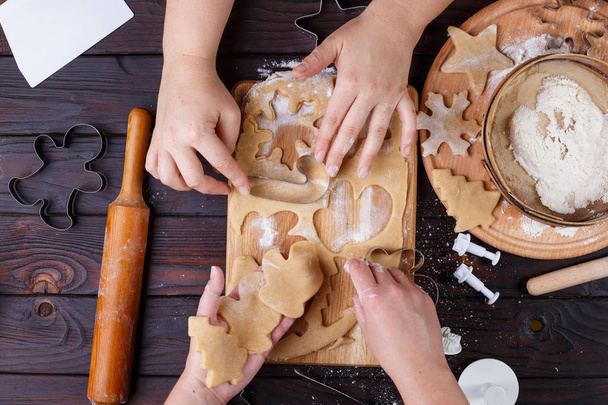 Christmas bakery. Friends cutting cookies of gingerbread dough,  - Foto, afbeelding