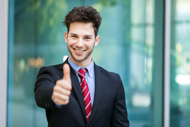 Young businessman showing thumb up outdoor - Photo, image