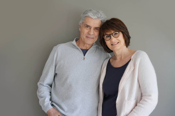Cheerful senior couple standing on grey background - Foto, afbeelding