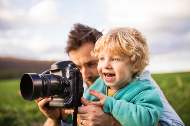 Bir baba ve yürümeye başlayan çocuk oğlu bahar doğa bir kamera ile. - Fotoğraf, Görsel