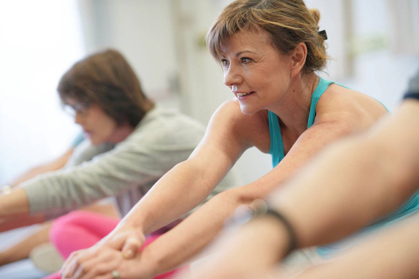 Portrait of senior woman in fitness class exercising on floor - Фото, изображение