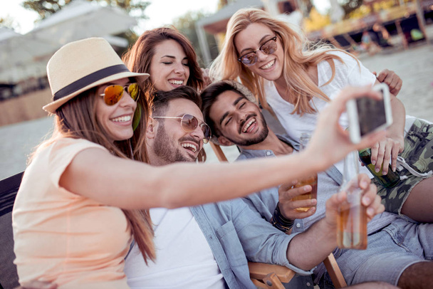 Groep vrienden nemen selfie met smartphone op strand - Foto, afbeelding