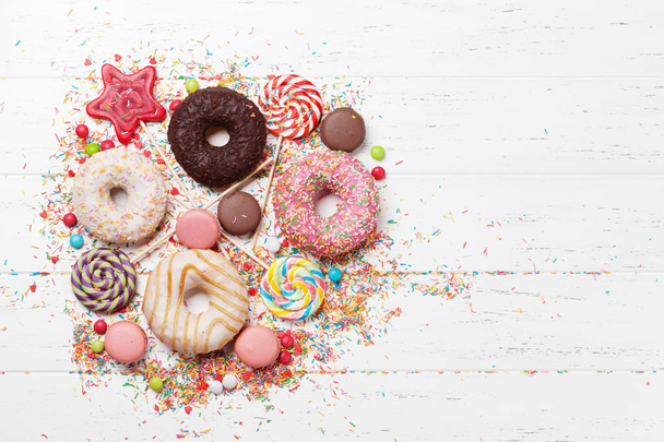 Colorful sweets. Lollipops, macaroons, candies, donuts. Top view with space for your text - Foto, Imagen