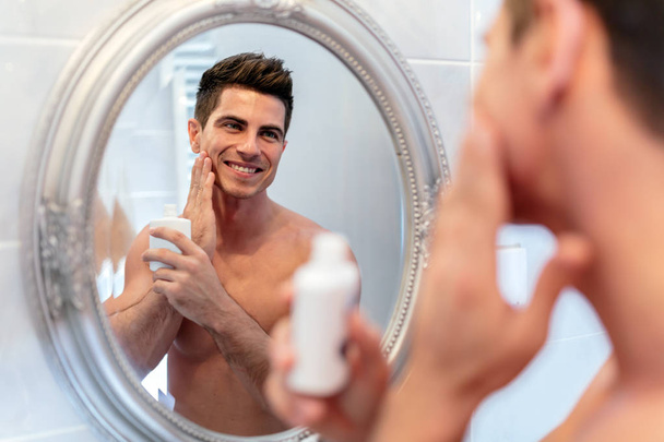 Handsome man looking in mirror after shaving - Foto, afbeelding