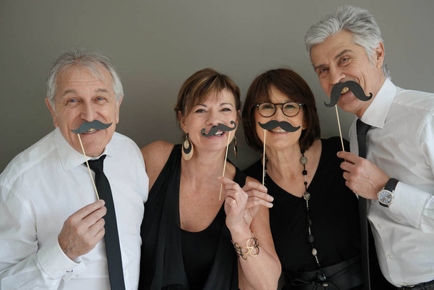 Senior people at a party having fun using photo props, isolated - Foto, Imagen