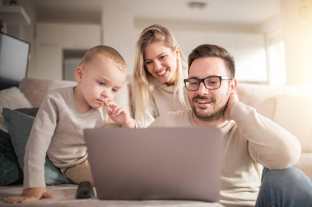Feliz familia joven viendo dibujos animados en el ordenador portátil juntos
. - Foto, Imagen