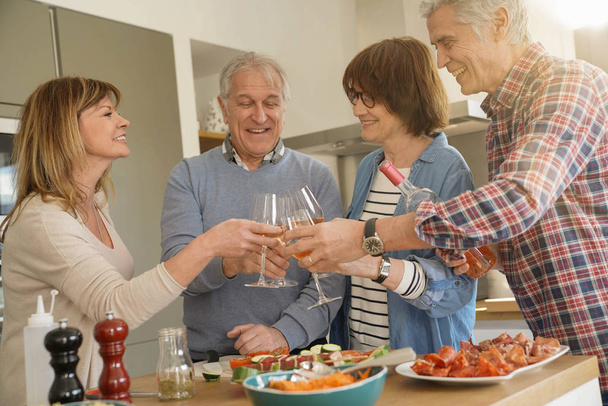 Senior people cheering with wine while preparing meal - Φωτογραφία, εικόνα