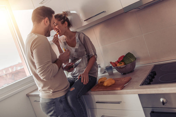 Casal preparando almoço juntos em sua cozinha.Pessoas, amor, diversão, felicidade, comida e bebida conceito
. - Foto, Imagem