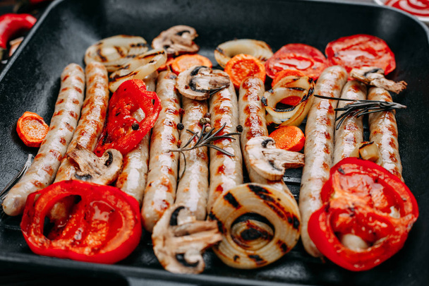 Saucisses grillées appétissantes et légumes servis dans un pa de friture
 - Photo, image