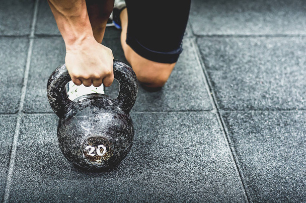 Muscular woman holding old and rusty kettlebell on to the gym floor for fitness training, real people workout no posing - Photo, Image