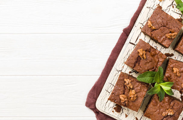 Postre de chocolate dulce Brownie con nueces y hojas significadas en tablero retro con espacio de copia sobre fondo beige pastel
. - Foto, Imagen