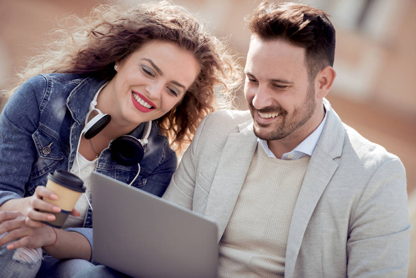 Portrait of loving couple relaxing and looking at laptop outdoors, having fun. - Photo, Image