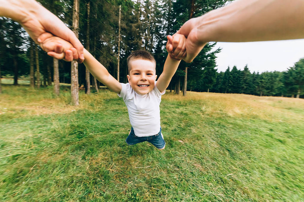 Father throwing his little son up in the air. Family time together. Happy little boy having fun with his dad outdoors - Photo, Image